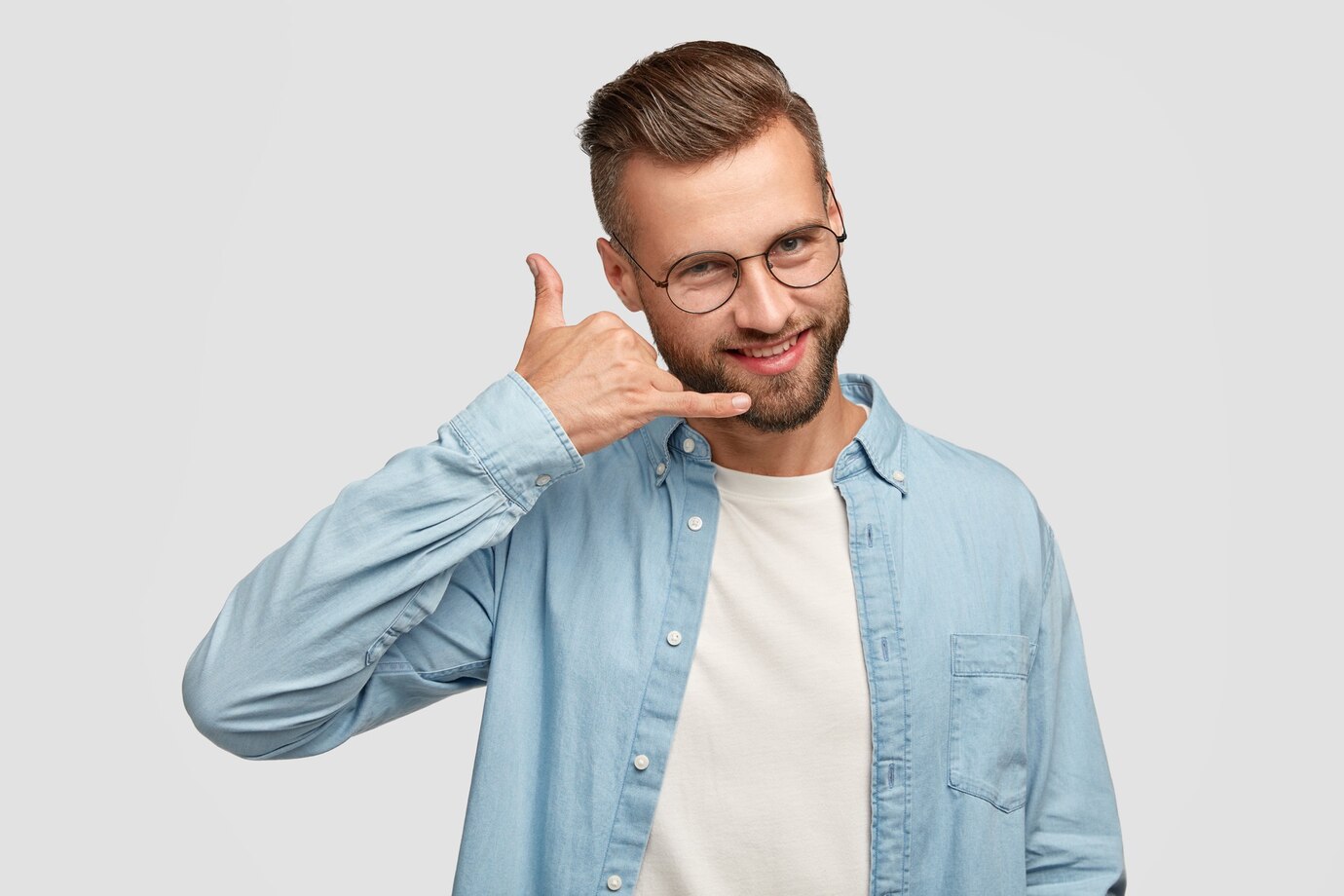 hombre-guapo-positivo-hace-gesto-telefono-finge-hablar-telefono-inteligente-tiene-expresion-alegre-vestido-camisa-moda-aislado-sobre-pared-blanca-concepto-personas-comunicacion_273609-16523